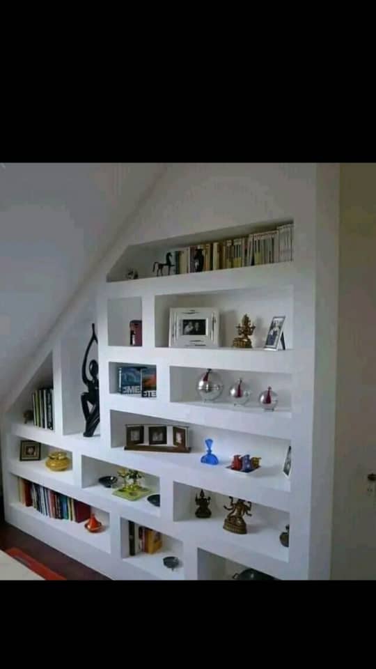 Built-in white POP shelving unit under a staircase